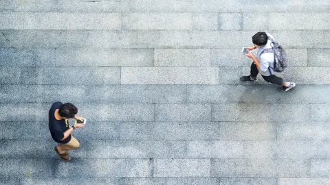 Aerial top view with blur man with smartphone walking converse with busy city crowd move to pedestrian crosswalk