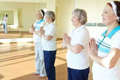 Portrait of two aged females doing yoga exercise for balance in sport gym 