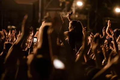 Large group of people cheering and having fun at music concert.