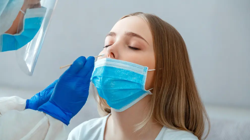 Doctor taking nasopharyngeal culture, PCR test to woman patient. Nurse take saliva sample through nose with cotton swab to check coronavirus covid 19. Long web banner.