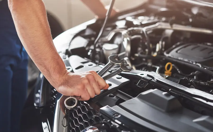 Picture showing muscular car service worker repairing vehicle.