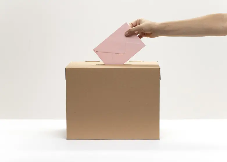 hand-puts-pink-envelope-into-vote-box