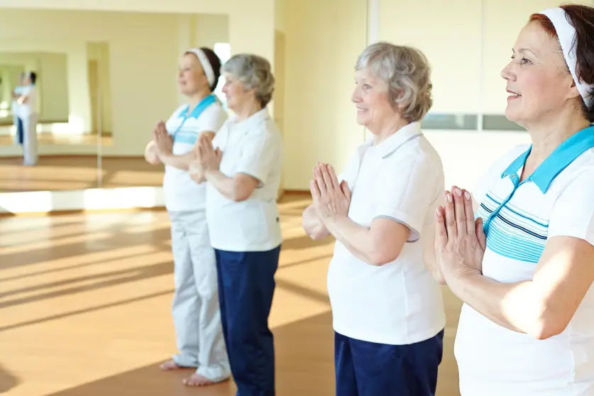 Portrait of two aged females doing yoga exercise for balance in sport gym 